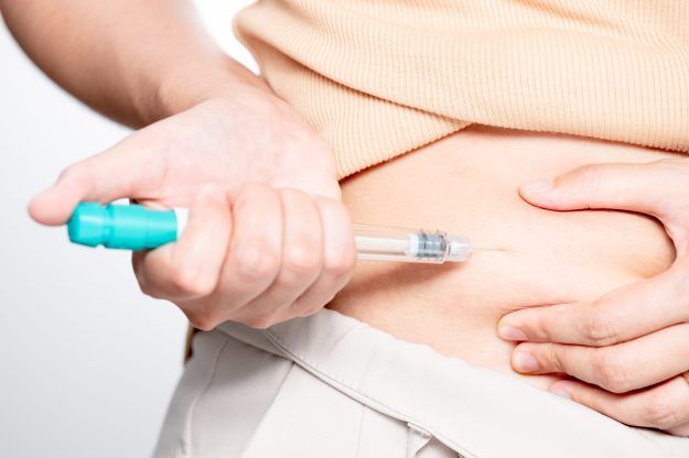Woman making hormonal therapy injection into her belly. Close up